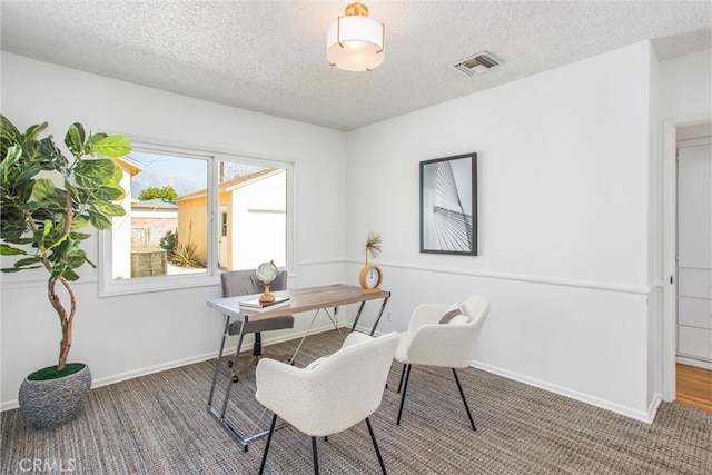 carpeted office space featuring baseboards, visible vents, and a textured ceiling