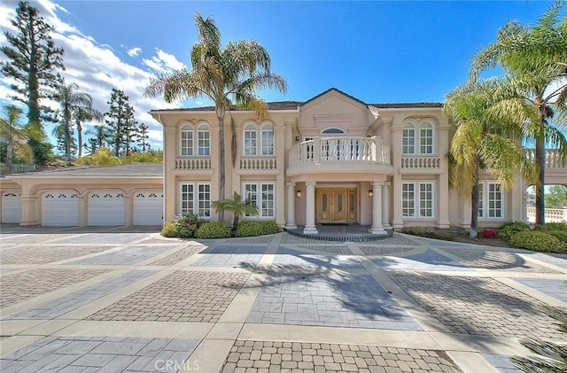 view of front facade with french doors, an attached garage, a balcony, and stucco siding