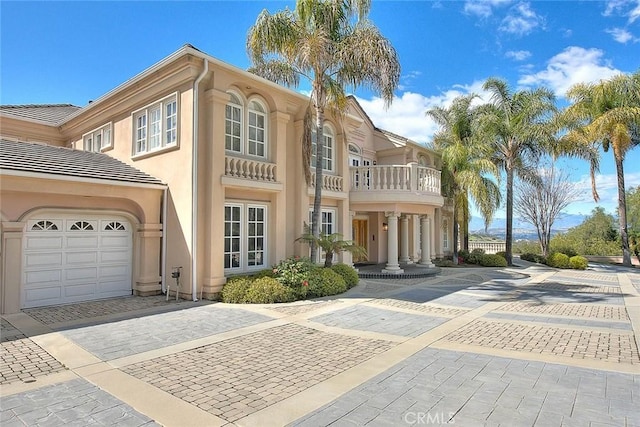 view of front facade with a garage, driveway, a balcony, and stucco siding