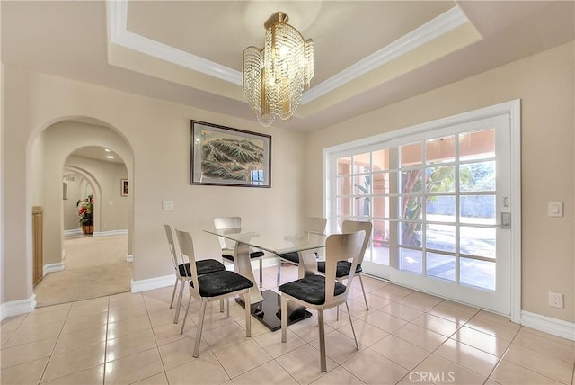 dining space featuring ornamental molding, a tray ceiling, and arched walkways