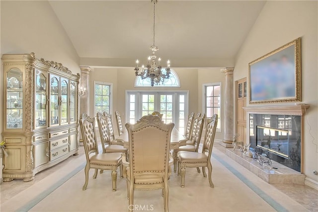 dining space featuring light carpet, a tile fireplace, french doors, ornate columns, and a notable chandelier