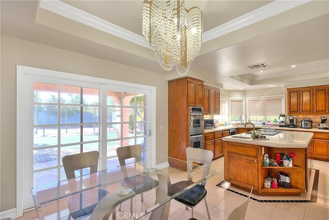 kitchen with brown cabinetry, light countertops, a raised ceiling, and visible vents