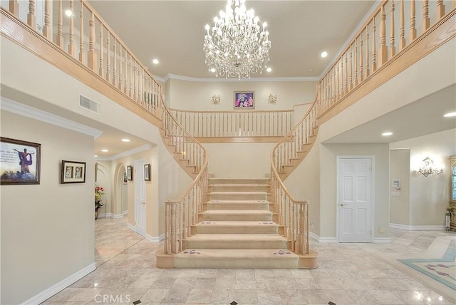 stairs featuring ornamental molding, a towering ceiling, visible vents, and baseboards