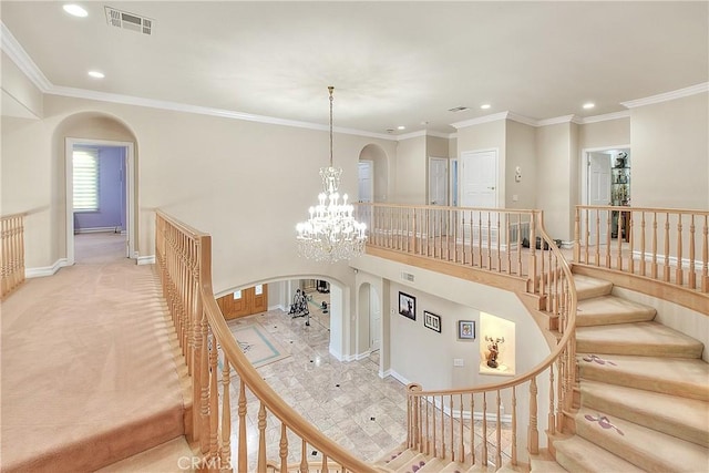 stairway featuring arched walkways, recessed lighting, a notable chandelier, visible vents, and crown molding