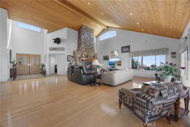 living room with wooden ceiling, high vaulted ceiling, light wood finished floors, and a stone fireplace