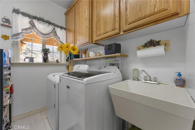 laundry room with washing machine and dryer, light tile patterned flooring, a sink, and cabinet space