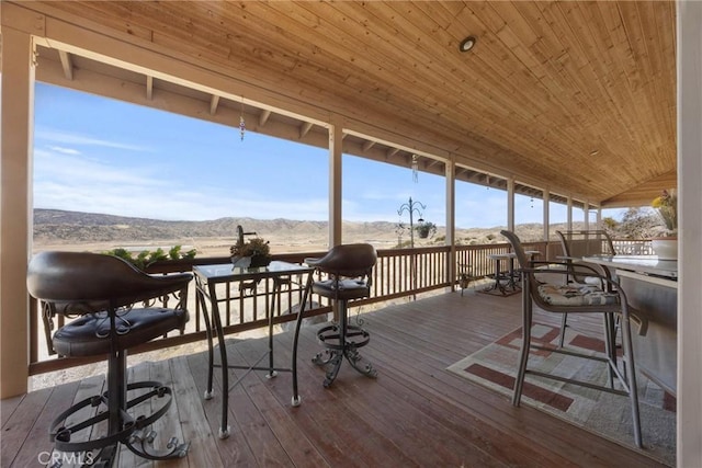 sunroom / solarium featuring vaulted ceiling, wooden ceiling, and a mountain view