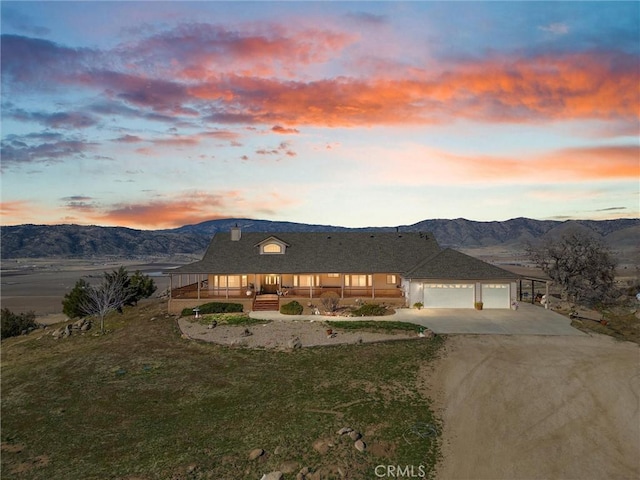 view of front of house featuring a garage, a mountain view, driveway, and a lawn