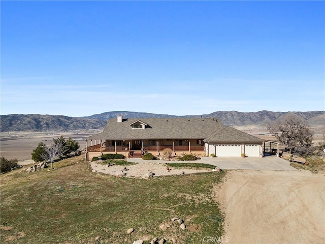 view of front of home with a mountain view, covered porch, a garage, driveway, and a front yard