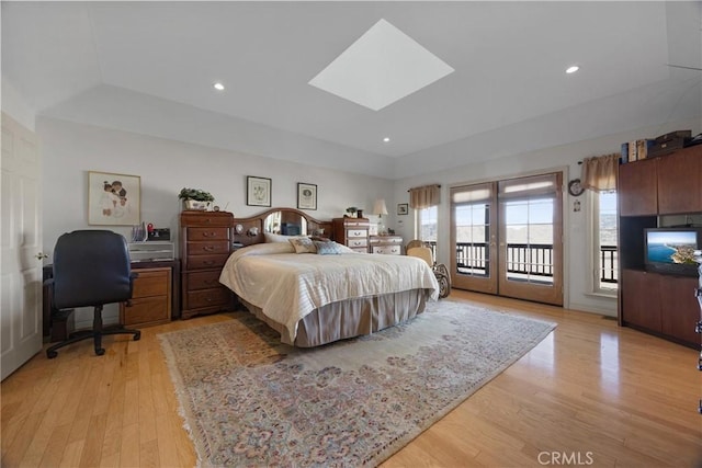 bedroom featuring access to exterior, a skylight, light wood-style floors, and recessed lighting