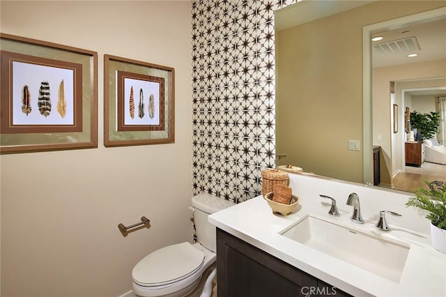 bathroom featuring toilet, visible vents, and vanity