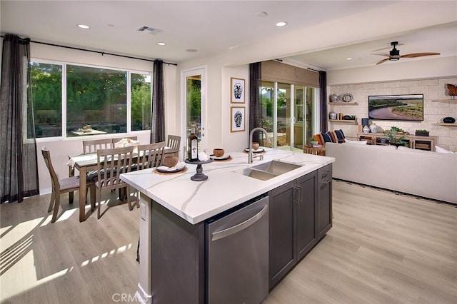 kitchen with a kitchen island with sink, visible vents, open floor plan, light countertops, and stainless steel dishwasher