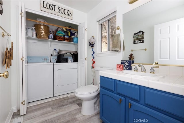 full bathroom featuring toilet, washing machine and dryer, wood finished floors, and vanity