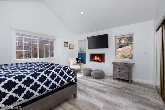 bedroom with high vaulted ceiling, recessed lighting, a fireplace, wood finished floors, and baseboards