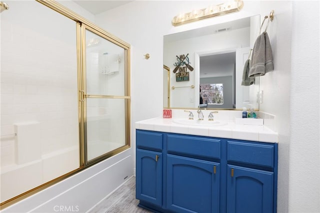 full bath with visible vents, shower / bath combination with glass door, vanity, and wood finished floors