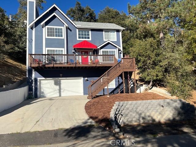 view of front of home featuring a chimney, concrete driveway, an attached garage, a deck, and stairs