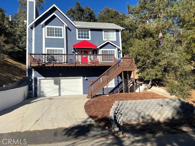 view of front of home with concrete driveway, stairs, a chimney, a garage, and a deck