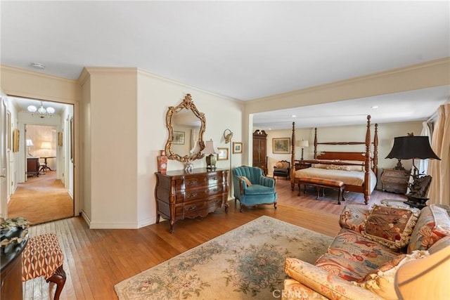 bedroom featuring a chandelier, light wood finished floors, baseboards, and crown molding