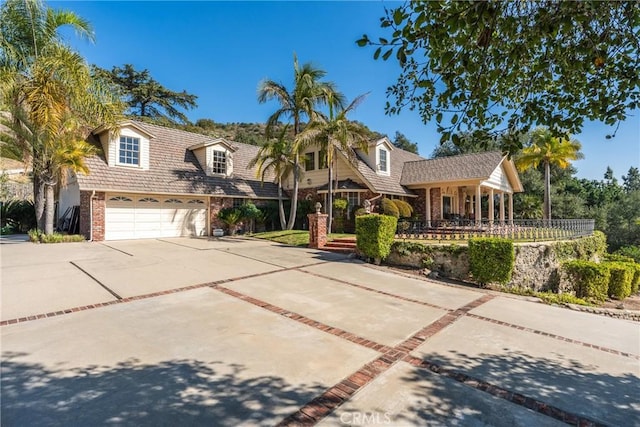 view of front of house featuring a garage, concrete driveway, brick siding, and covered porch