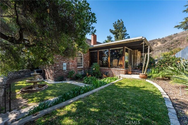 rear view of property with a yard, a chimney, fence, and brick siding