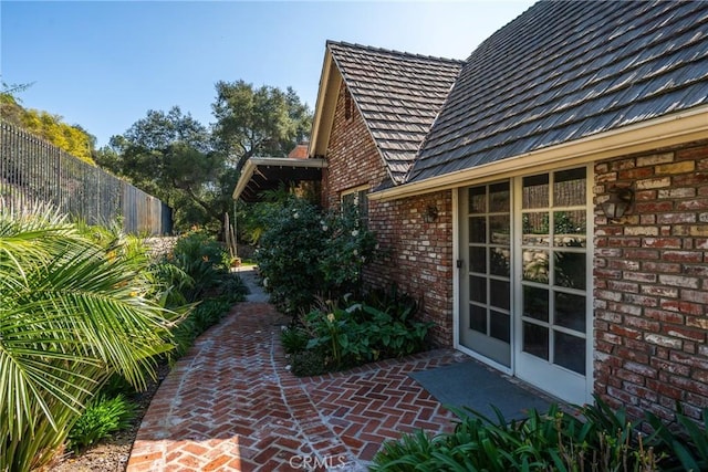 exterior space featuring a patio area, fence, and brick siding