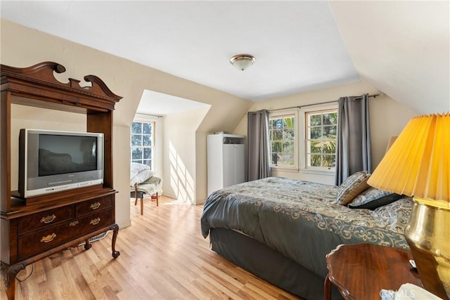 bedroom with light wood-style floors, multiple windows, and vaulted ceiling