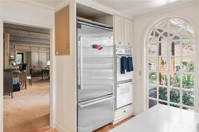 kitchen with light carpet, stainless steel built in fridge, light countertops, double oven, and white cabinetry