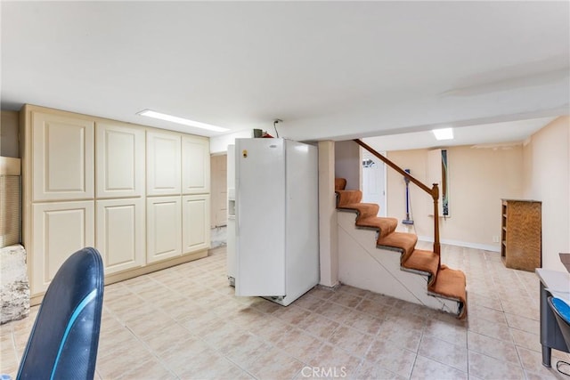 finished basement with stairs and white fridge with ice dispenser