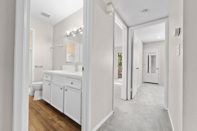 hall featuring carpet, visible vents, a sink, and baseboards