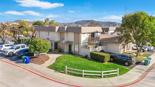 view of property featuring a residential view, a mountain view, a front yard, and stucco siding