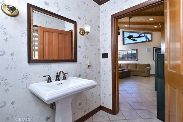 bathroom with wallpapered walls, baseboards, vaulted ceiling with beams, tile patterned flooring, and a sink