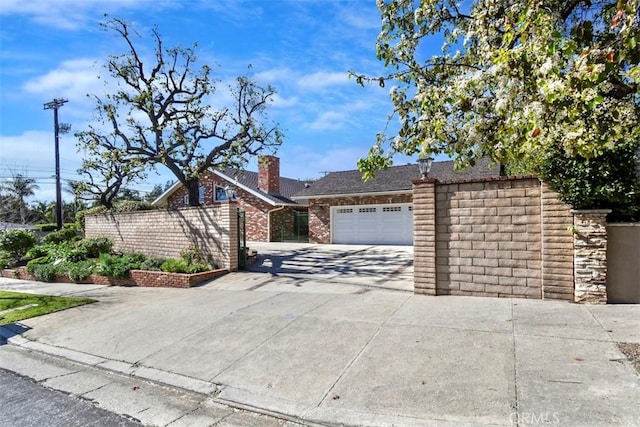 view of front of house with concrete driveway, stone siding, an attached garage, and fence