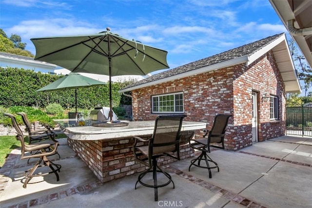 view of patio / terrace featuring a grill, fence, area for grilling, and exterior bar