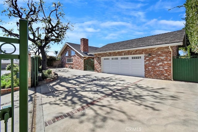 view of front of home with brick siding, driveway, an attached garage, and fence