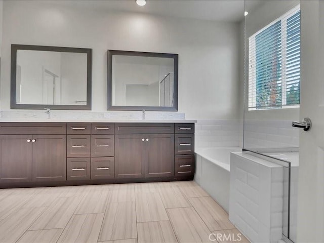 bathroom featuring a sink, double vanity, and a garden tub