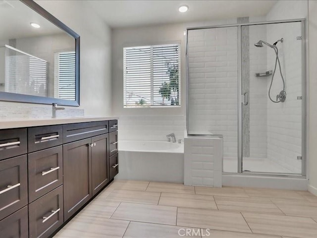 bathroom with a shower stall, a bath, and vanity