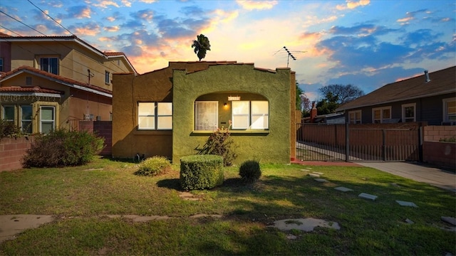 view of side of home featuring a yard, fence, and stucco siding