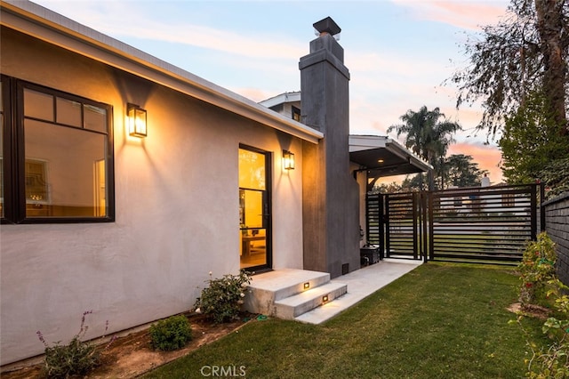 exterior space with stucco siding, fence, and a yard