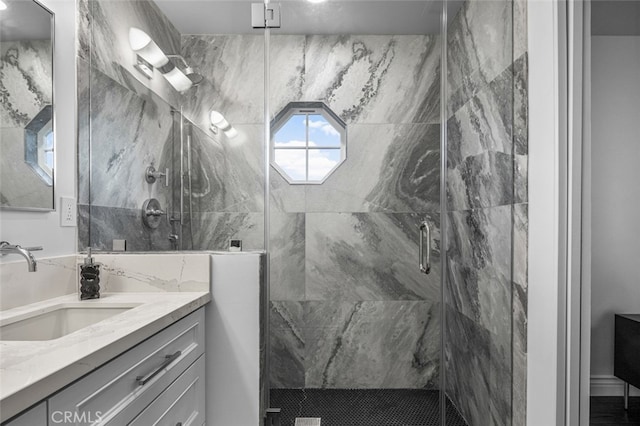 full bath featuring a marble finish shower and vanity