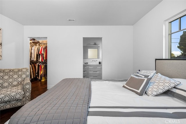 bedroom with wood finished floors, a closet, a walk in closet, and visible vents