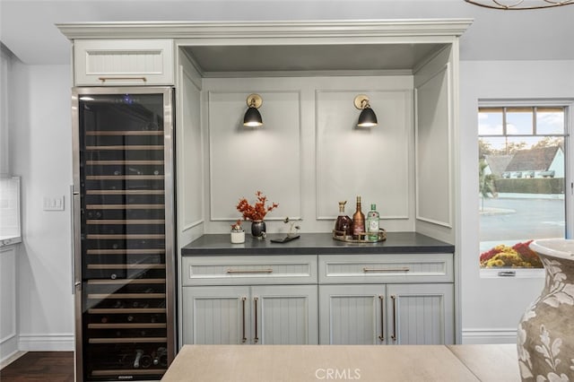 bar featuring wine cooler, dark wood-style flooring, a dry bar, and baseboards