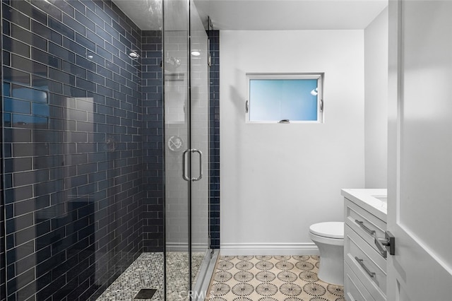 bathroom featuring toilet, a shower stall, baseboards, and vanity