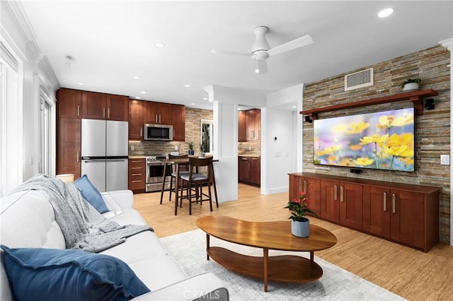 living area with crown molding, recessed lighting, visible vents, a ceiling fan, and light wood-type flooring