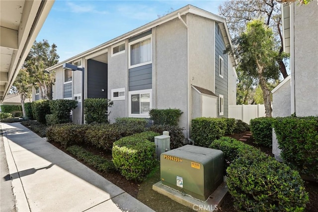 view of side of property featuring fence and stucco siding