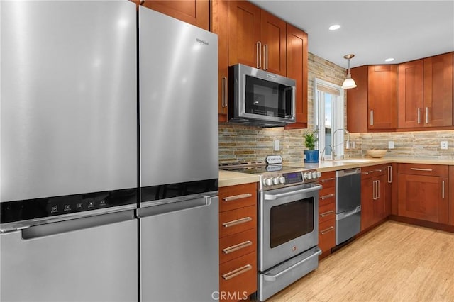 kitchen featuring a sink, stainless steel appliances, light countertops, and decorative light fixtures