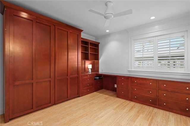 unfurnished office with crown molding, built in desk, recessed lighting, light wood-style floors, and ceiling fan