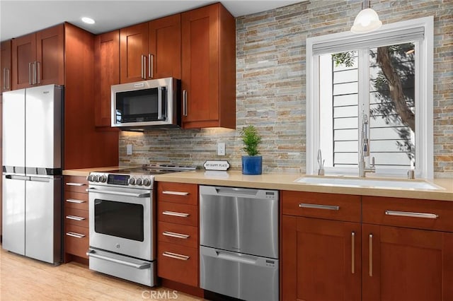 kitchen with appliances with stainless steel finishes, light countertops, backsplash, and pendant lighting