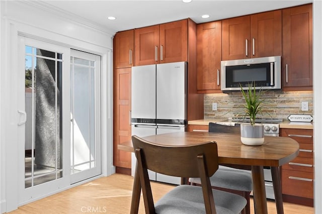 kitchen featuring light countertops, stainless steel microwave, plenty of natural light, and decorative backsplash