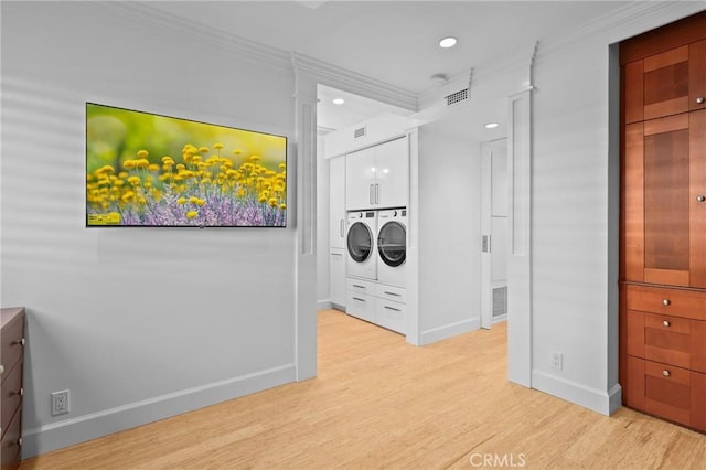 clothes washing area featuring crown molding, washing machine and clothes dryer, light wood-style flooring, laundry area, and baseboards