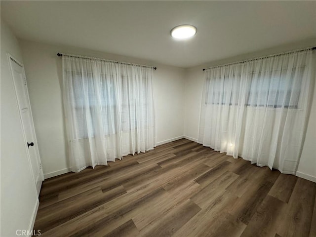 empty room featuring baseboards and dark wood-style flooring